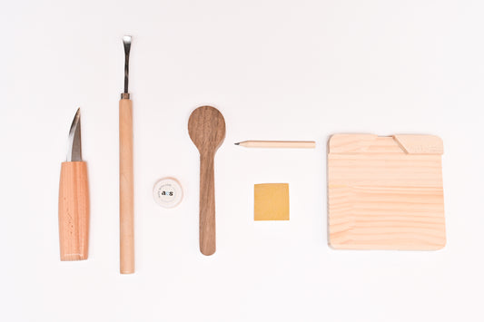 Close-up of spoon carving tools and wooden materials included in the A Collective Space DIY carving kit.