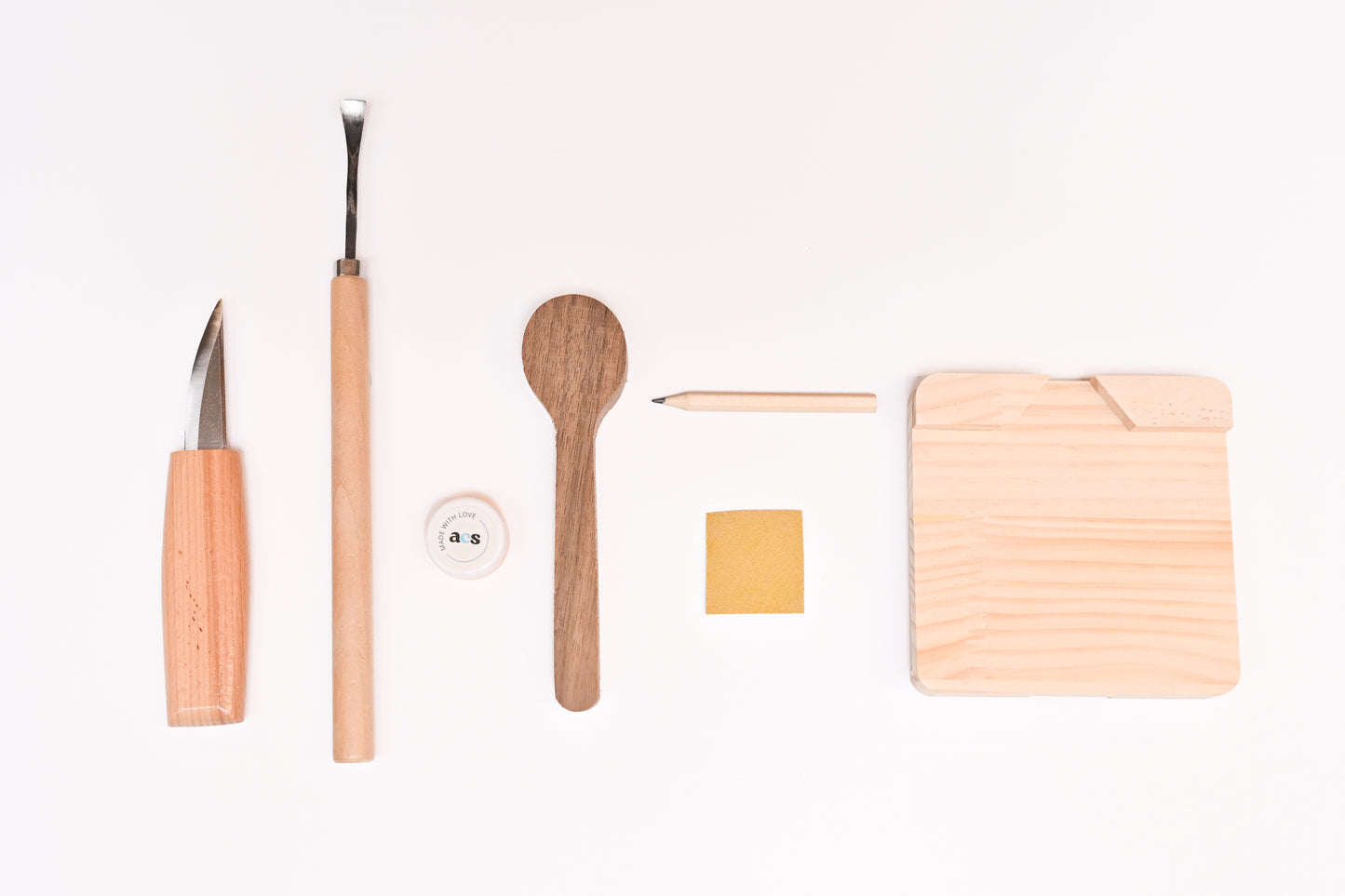 Close-up of spoon carving tools and wooden materials included in the A Collective Space DIY carving kit.