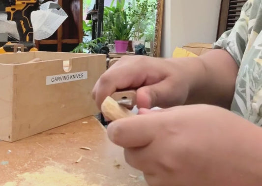 Hands carving a wooden spoon.